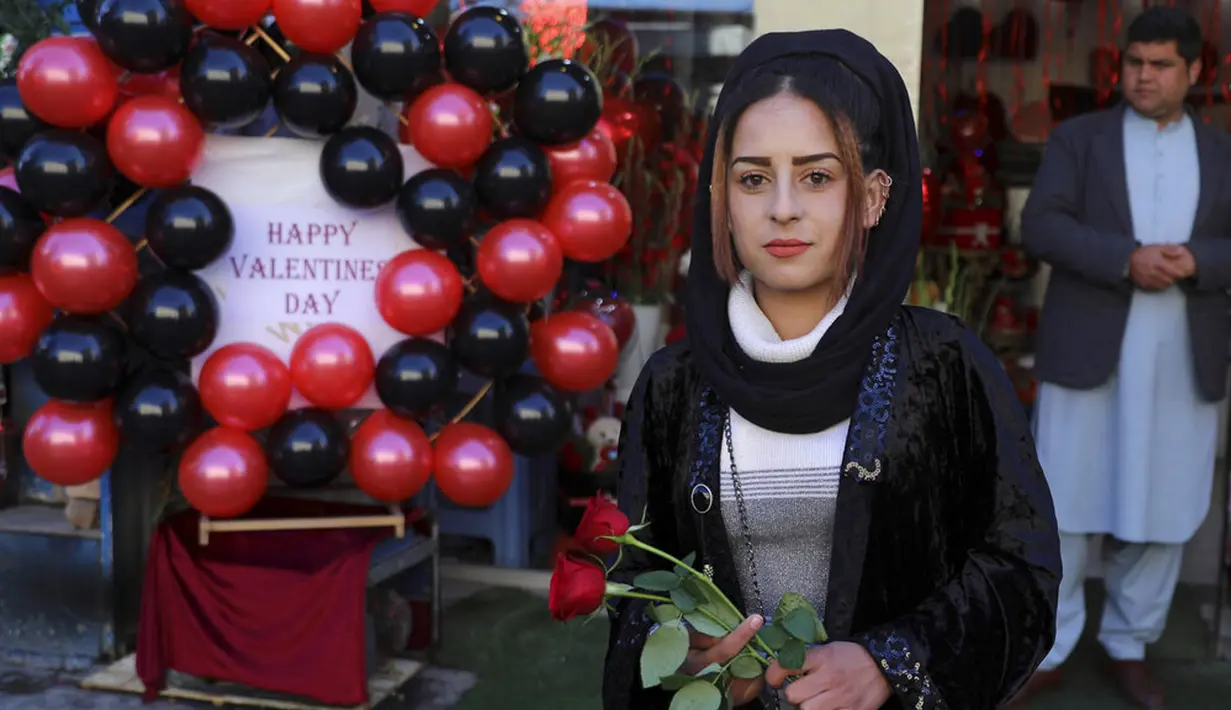 Seorang wanita berpose sambil memegang mawar untuk merayakan Hari Valentine di Kabul, Afghanistan, Minggu (14/2/2021). Hari Valentine menjadi budaya baru dalam masyarakat Afghanistan yang konservatif. (AP Photo/Rahmat Gul)