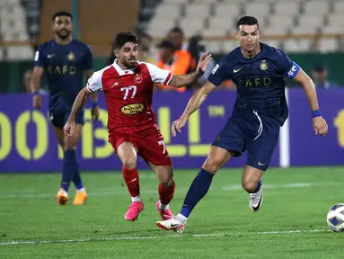 Pemain Al-Nassr, Cristiano Ronaldo (kanan) menggiring bola melewati pemain Persepolis, Mohammad Omri pada laga Grup E Liga Champions Asia 2023/2024 yang berlangsung di Azadi stadium, Teheran, Iran, 19 September 2023. (AFP/Atta Kenare)