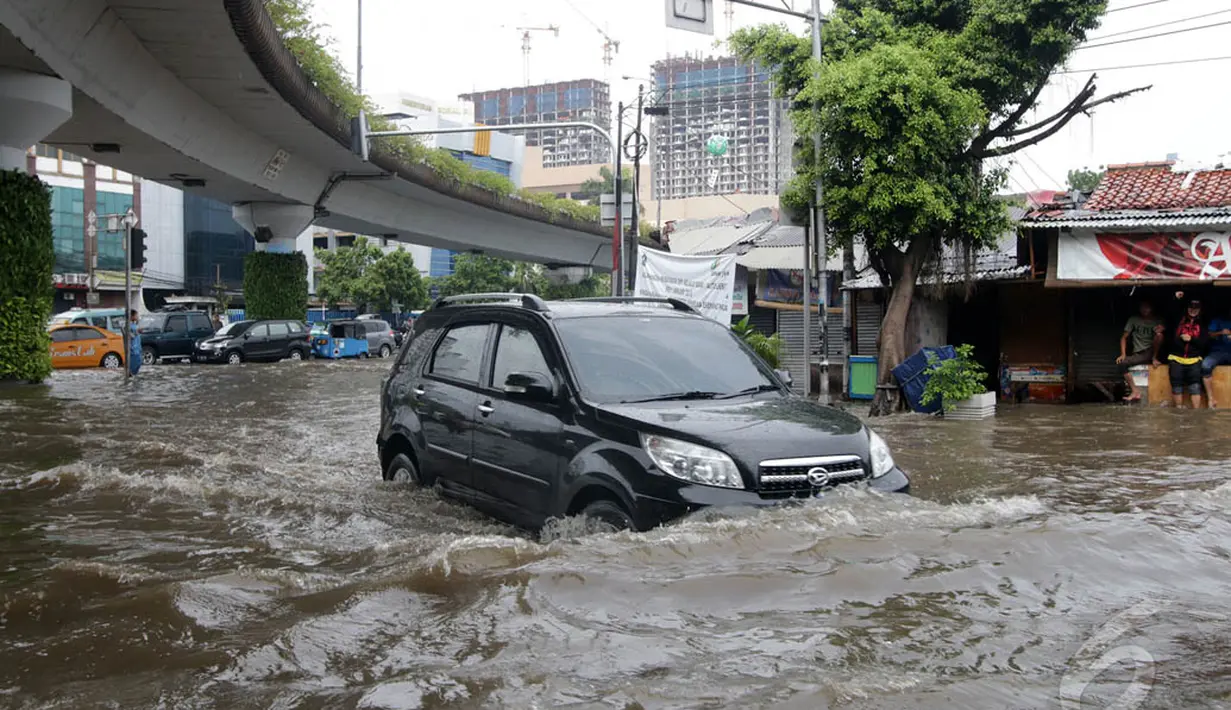 Sebuah mobil tampak nekat melintasi Jalan Matraman, Jakarta,  yang digenangi air, Sabtu (27/12/2014). (Liputan6.com/Miftahul Hayat)