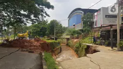 Jalan ambles di ruas Jalan Boulevard, Grand Depok City (GDC), Kota Depok, Jawa Barat, Selasa (13/4/2021). Jalan tersebut ambles ke aliran sungai sedalam 3 hingga 5 meter. (Liputan6.com/Herman Zakharia)