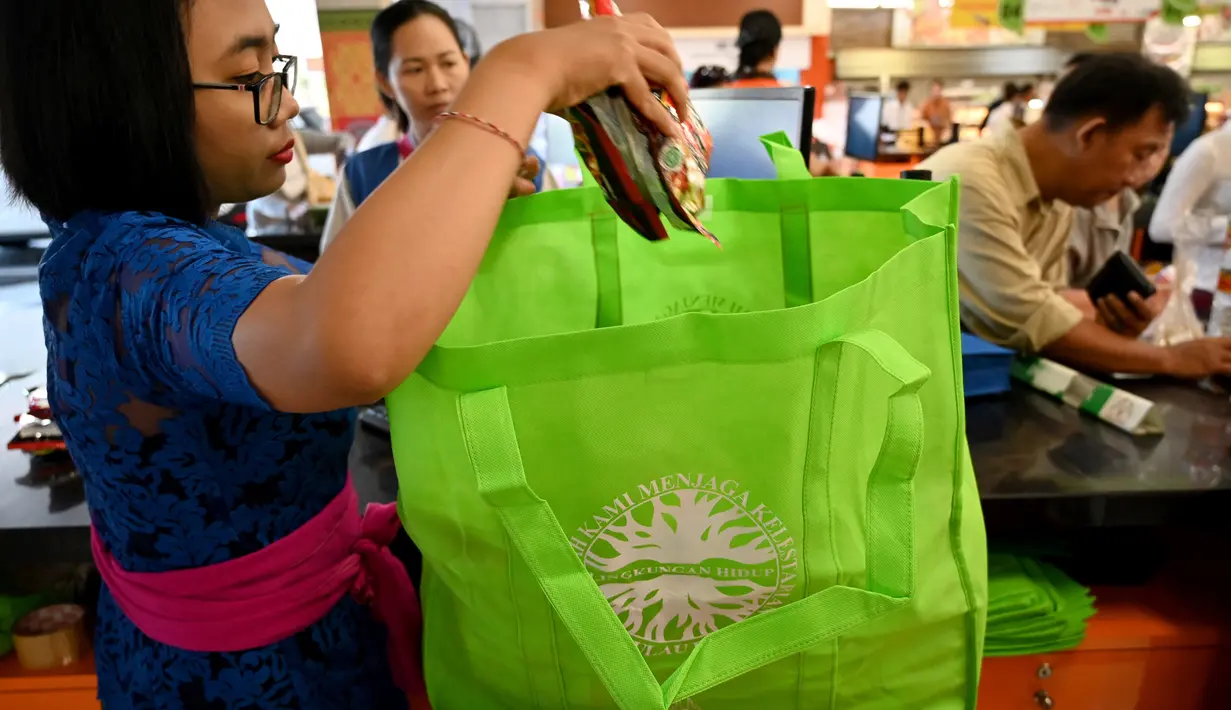 Karyawan mengemas barang belanjaan konsumen dengan tas belanja nonplastik di sebuah supermarket di Denpasar, 16 Juli 2019. Bali menerapkan pelarangan penggunaan plastik sekali pakai yang tertuang dalam Peraturan Gubernur (Pergub) Nomor 97 Tahun 2018. (SONNY TUMBELAKA/AFP)