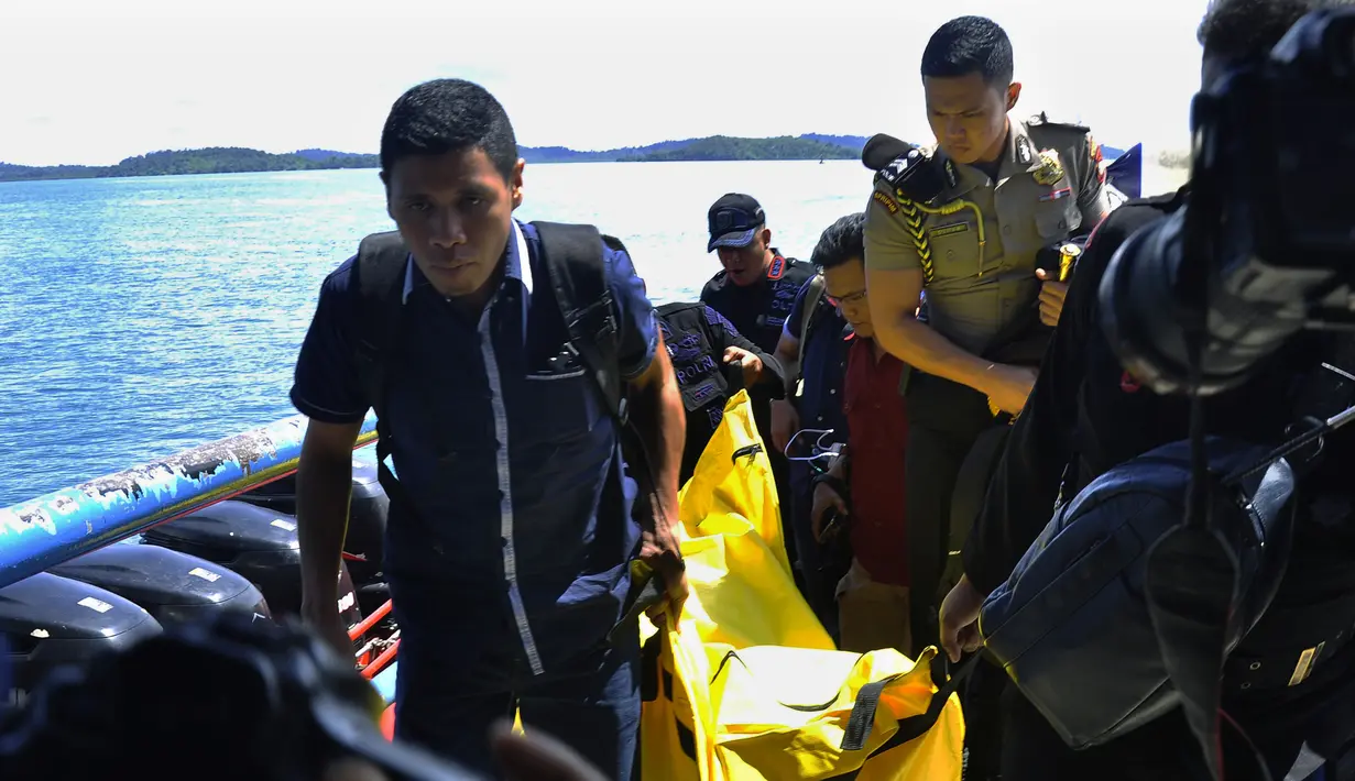 Anggota kepolisian bersiap turun dari kapal sambil mengangkat kantong jenazah berisi puing-puing dan barang-barang dari jatuhnya pesawat jenis M-28 Skytrcuk milik Polri di Pelabuhan Telaga Punggur, Batam, Kepri, Minggu (4/12). (Rezza HERDIYANTO/AFP)