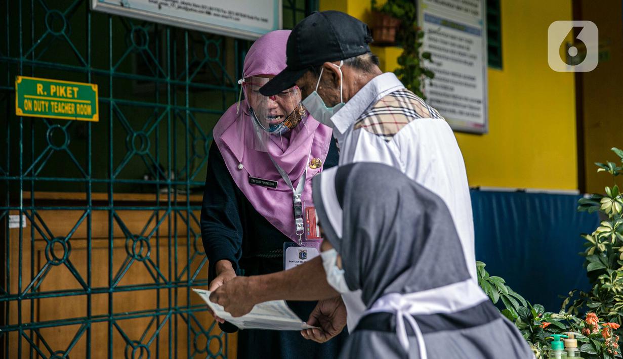 Warga berbincang dengan petugas saat mengambil Bantuan Sosial Tunai (BST) di SMAN 111, Jakarta, Selasa (19/1/2021). Pemprov DKI Jakarta menyalurkan BST sebesar Rp 300 ribu kepada 1.055.216 KK mulai Januari hingga April 2021. (Liputan6.com/Faizal Fanani)
