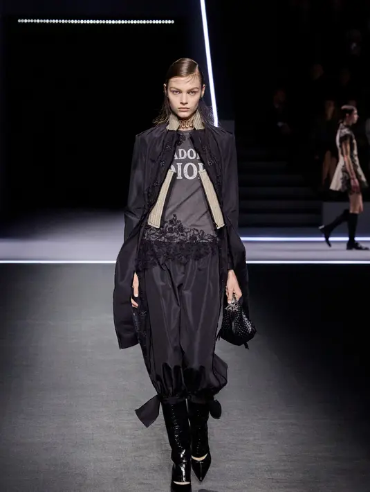 Salah satu kejutan dalam koleksi ini adalah kembalinya kaos J’adore Dior rancangan John Galliano. Bordir potongan, aplikasi detail, dan pita beludru hitam dengan mutiara barok menambah tekstur pada rok dan gaun, memberikan sentuhan klasik yang segar.  [Dok/Dior],