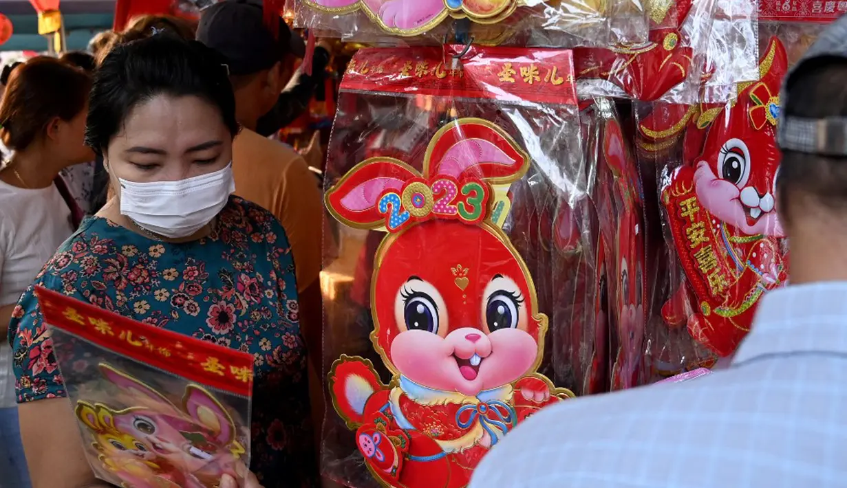 Pelanggan melihat dekorasi di kios pasar jalanan jelang Tahun Baru Imlek di Distrik Pecinan Yangon, Myanmar, 18 Januari 2023. Tahun Baru Imlek 2023 yang disebut sebagai Tahun Kelinci akan jatuh pada tanggal 22 Januari. (STRINGER/AFP)