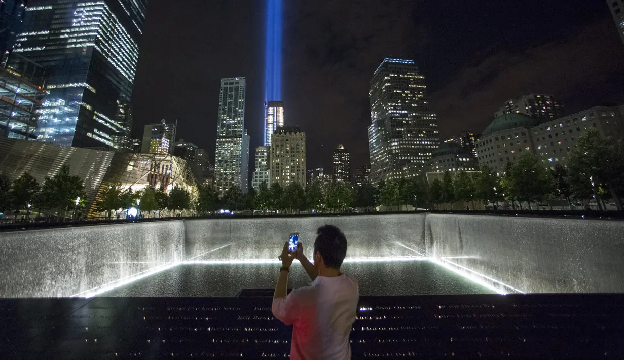 Seorang pengunjung mengabadikan lampu sorot dipancarkan ke langit dari World Trade Center (WTC) kota New York, AS, (9/9/2015). Acara Tribute in Light memperingati 14 tahun tragedi terorisme 11 September di Amerika Serikat. (REUTERS/Andrew Kelly)