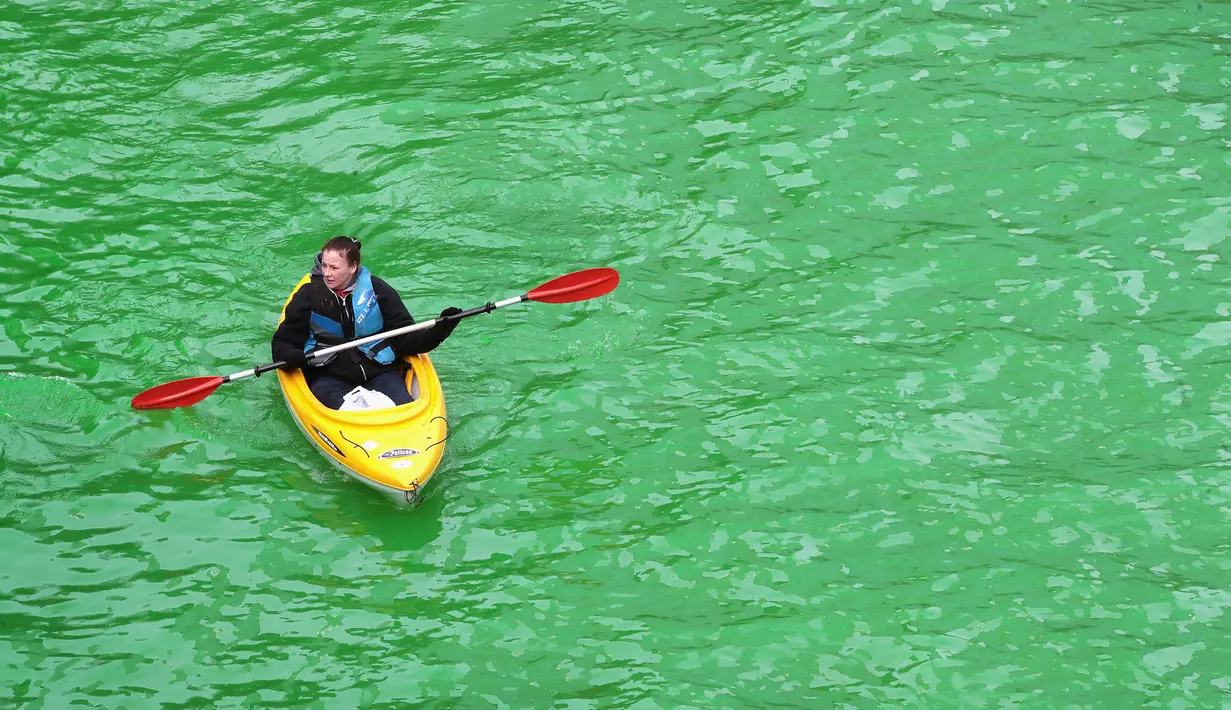 Sebuah perahu kayak melintasi Sungai Chicago yang berubah hijau pada peringatan hari Santo Patrick di Illinois, Sabtu (17/3). Hari raya Santo Patrick diperingati setiap tanggal 17 Maret yang diidentikkan dengan warna hijau. (Scott Olson/Getty Images/AFP)