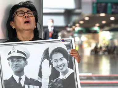 Seorang pelayat Thailand, Kanjana Malaithong, memegang potret Ratu Thailand yang telah wafat, Sirikit Kitiyakara, dan Raja Thailand Bhumibol Adulyadej, sambil menangis di Rumah Sakit Chulalongkorn di Bangkok pada 25 Oktober 2025. (Chanakarn Laosarakham/AFP)