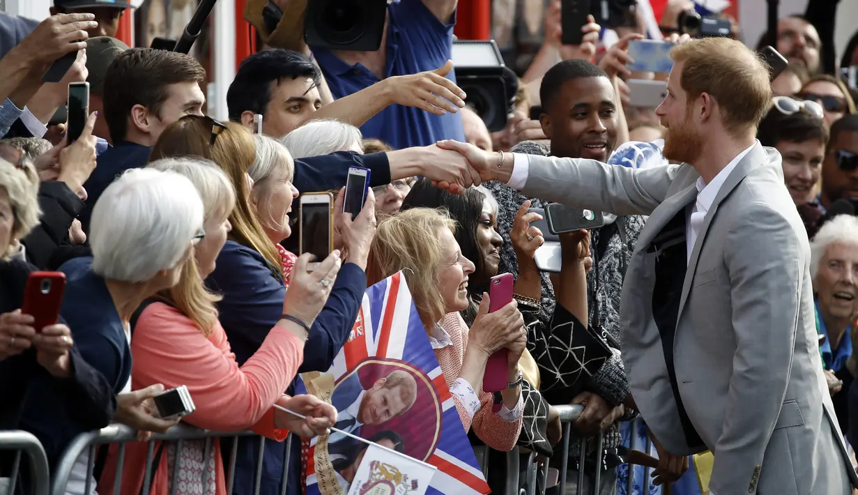 Pangeran Harry menyapa orang-orang di luar Kastil Windsor, Inggris, Jumat (18/5). Pangeran Harry dan Meghan Markle akan menikah di Kastil Windsor. (Aneh ANDERSEN/AFP)