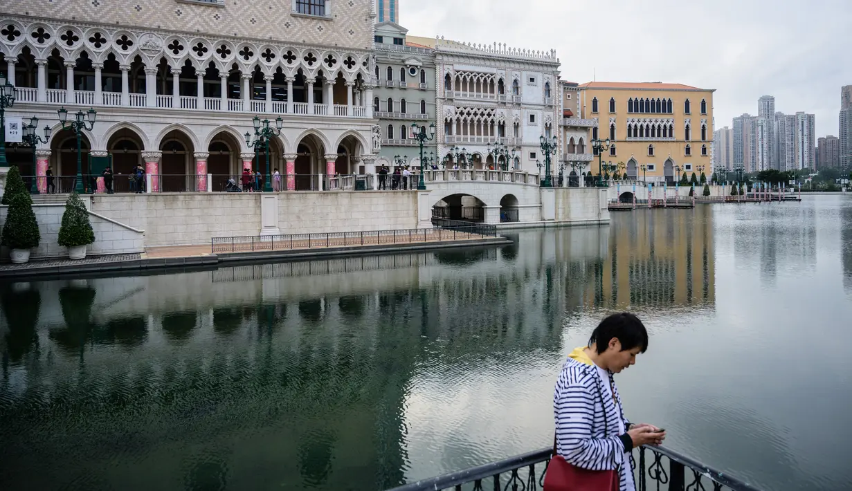 Seorang pria memakai ponselnya di luar resor kasino The Venetian, Macau, 5 Maret 2019. Pada sensus 2016, penduduk Macau berjumlah sekitar 600 ribu orang. (Anthony Wallace/AFP)