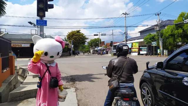 Menggunakan boneka karakter binatang kelinci, nampak seorang pengamen boneka tengah menghibur pengguna jalan, saat berhenti di lampu merah Terusan Pembangunan, Garut, Jawa Barat.