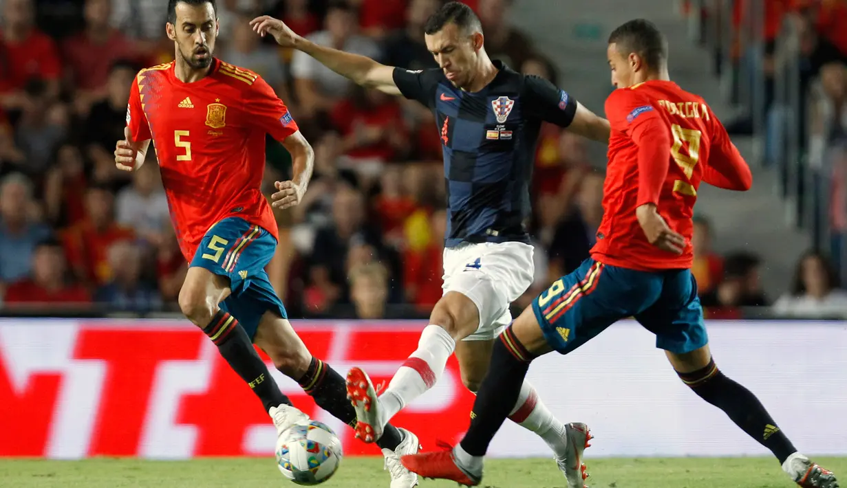 Gelandang Kroasia, Ivan Perisic berusaha melewati dua pemain Spanyol saat bertanding pada UEFA Nations League di stadion Manuel Martinez Valero, Spanyol (11/9). Spanyol menang telak atas Kroasia 6-0. (AP Photo/Alberto Saiz)