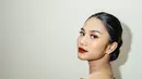 Area matanya dipertajam dengan winged eyeliner tipis, rambutnya ditata sleek look dengan sanggul rendah dan pulasan lipstik merah. [Foto: Instagram/azizahsalsha_]