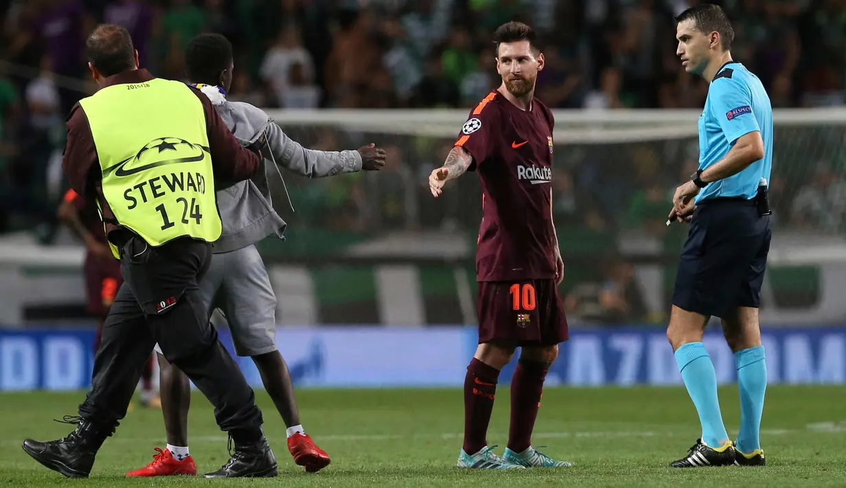 Petugas membawa seorang suporter yang mencium kaki kiri Lionel Messi saat pertandingan grup D Liga Champions melawan Sporting CP di stadion Alvalade, Lisbon, (27/9). (AP Foto/Armando Franca)