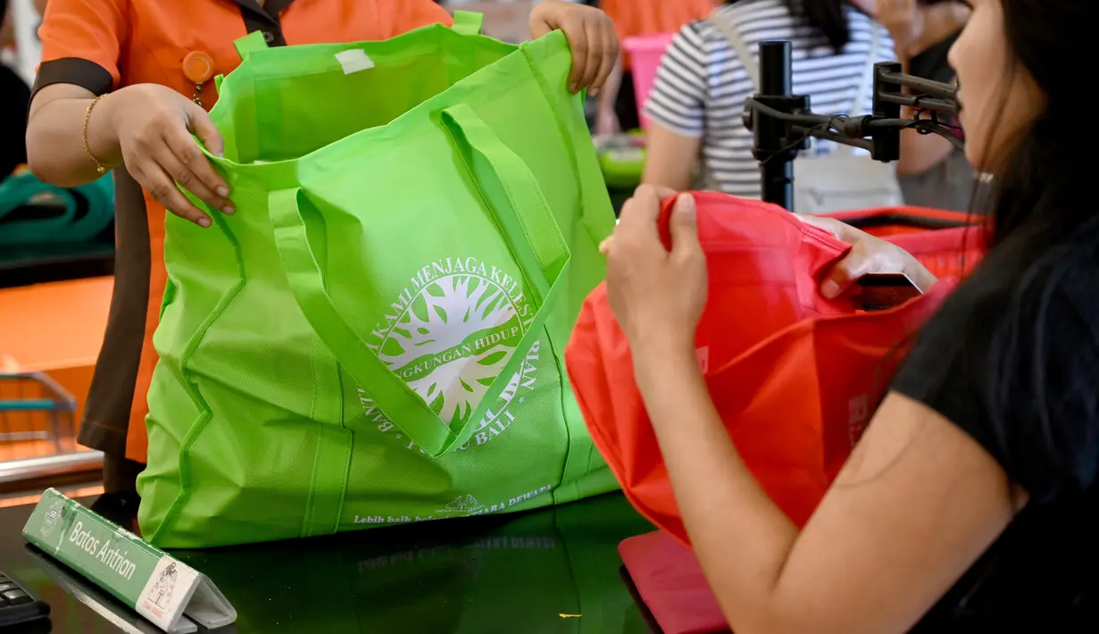 Karyawan mengemas barang belanjaan konsumen dengan tas belanja nonplastik di sebuah supermarket di Denpasar, 16 Juli 2019. Bali menerapkan pelarangan penggunaan plastik sekali pakai yang tertuang dalam Peraturan Gubernur (Pergub) Nomor 97 Tahun 2018. (SONNY TUMBELAKA/AFP)