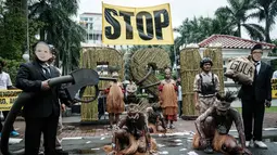 Mereka menilai proyek ini sebagai solusi palsu yang mengancam hutan alam dan ruang hidup masyarakat adat demi ambisi bioetanol. Tampak dalam foto, aktivis Greenpeace Indonesia bersama beberapa pemuda Papua menggelar aksi teatrikal saat berunjuk rasa di depan Kantor Kementerian Koordinator bidang Perekonomian, Jakarta, Kamis (18/12/2025). (Yasuyoshi Chiba/AFP)
