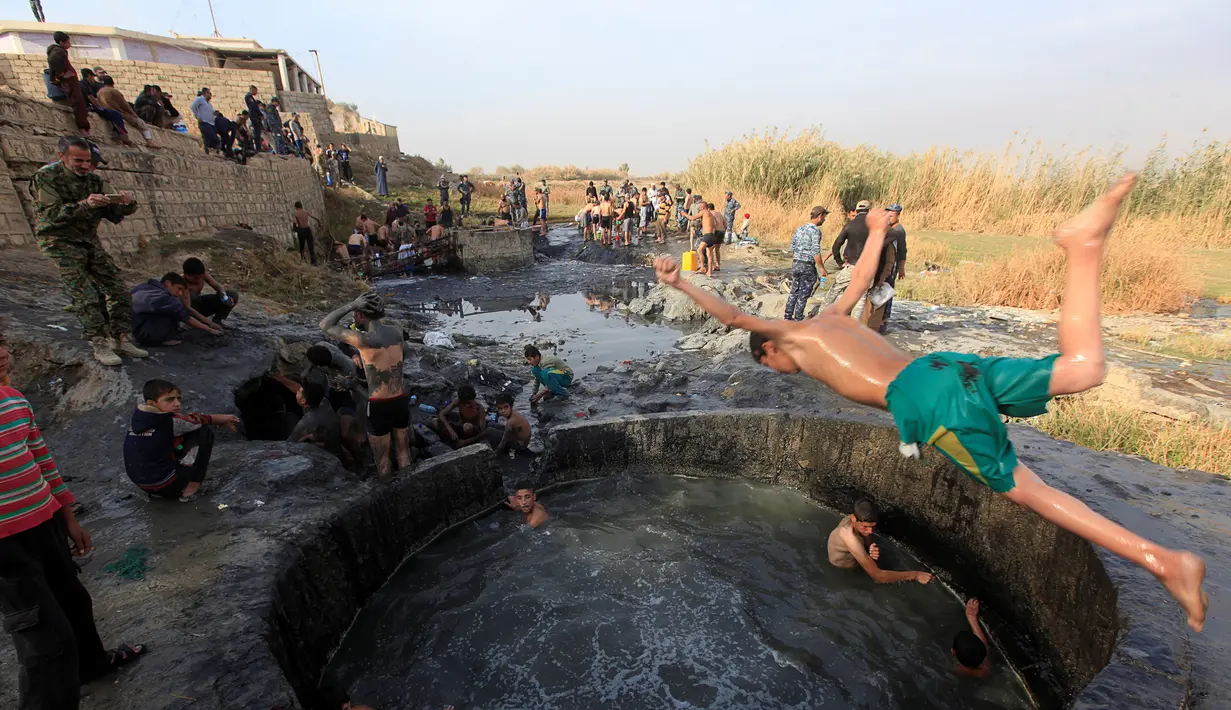 Seorang tentara Irak melompat ke kolam belerang di Hammam al-Ali, Mosul, Irak, (9/11). Di tengah perang melawan ISIS, mereka melepaskan penat dan lelah dengan berenang di Kolam belerang. (REUTERS/Alaa Al-Marjani)