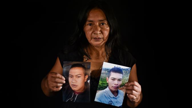 Lucila Huila, ibu dua dari enam pria Kolombia yang dibantai oleh terduga kelompok bersenjata pada 21 Agustus di El Tambo, berpose dengan foto putranya Heine Collazos, 25, dan Esneider Collazos, 23, di Popayan pada 28 Agustus 2020. Pembunuhan kembali berdarah di pedesaan Kolombia. (Luis ROBAYO/AFP)