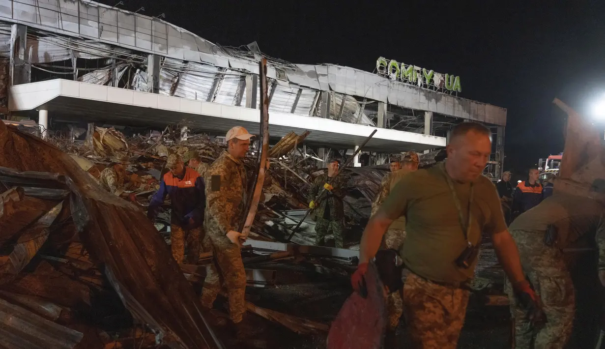 Sejumlah relawan bekerja untuk mengambil puing-puing di pusat perbelanjaan yang terbakar setelah serangan roket di Kremenchuk, Ukraina, Selasa (28/6/2022) pagi. (AP Photo/Efrem Lukatsky)