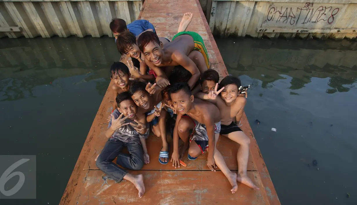 Keseruan anak-anak berfoto saat bermain dan mandi di anak Kali Ciliwung, Jakarta, Rabu (13/7). Bersihnya kali yang berada di Ibu Kota itu dimanfaatkan anak-anak sekitar untuk berenang sambil mengisi waktu libur sekolah. (Liputan6.com/Immanuel Antonius)