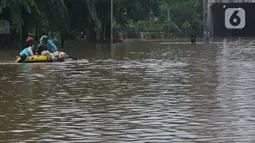 Warga menaiki perahu karet saat melintasi kawasan DI Panjaitan, Jakarta, Selasa (25/2/2020). Hujan yang mengguyur Jakarta sejak dini hari tadi membuat kawasan tersebut terendam banjir sehingga tak bisa dilintasi kendaraan bermotor. (Liputan6.com/Herman Zakharia)