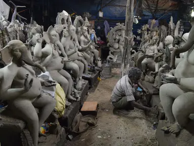 Perajin membuat patung Dewa Ganesha di sebuah bengkel di pinggiran Hyderabad, India, Rabu (18/8/2021). ​Patung ramah lingkungan yang dibuat jelang perayaan Ganesh Chaturthi tersebut dibuat dari lumpur, serat rami, dan bambu untuk mengurangi polusi air. (NOAH SEELAM/AFP)