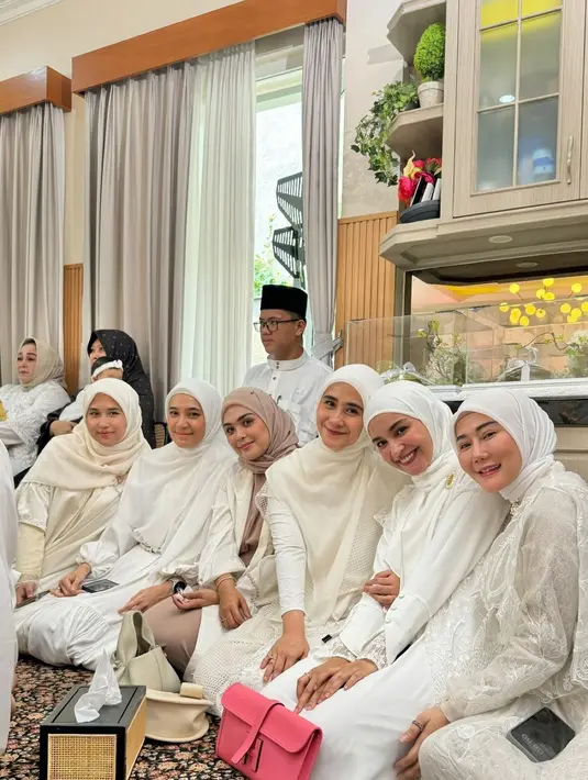 Ryana Dea kenakan dress putih panjang dengan vest jaring-jaring saat hadiri pernikahan Irish Bella. Dipadukan dengan hijab segitiga dengan clutch berwarna beige [@ryana_dea]