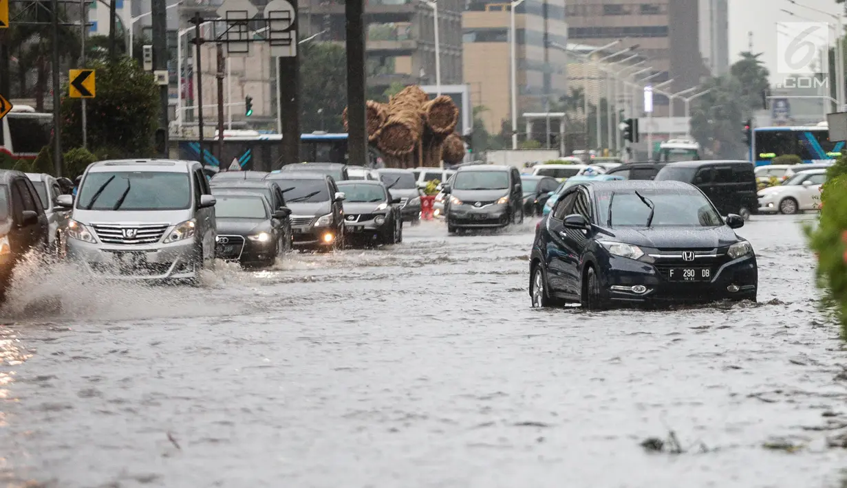 Sejumlah kendaraan melintas menerjang genangan air di kawasan Bunderan HI, Jakarta, Kamis (22/11). Genangan air hujan setinggi 40 cm tersebut disebabkan hujan deras yang melanda Jakarta pada siang hari. (Liputan6.com/Faizal Fanani)
