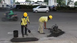 Petugas menambal lubang pada jalan yang rusak di kawasan Jatinegara, Jakarta, Kamis (7/2). Musim hujan yang mengguyur Jakarta selama beberapa waktu terakhir meninggalkan kerusakan pada sejumlah ruas jalan di Ibukota. (Liputan6.com/Immanuel Antonius)