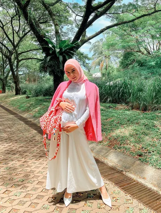 Menggunakan busana serba putih dan dipadukan blazer berwarna baby pink, penampilan Irish Bella yang pamer baby bump ini juga juga curi perhatian netizen. Dirinya pun memilih memakai gaya hijab sederhana berwana senada dengan blazer serta tas yang digunakan. (Liputan6.com/IG/@_irishbella_)