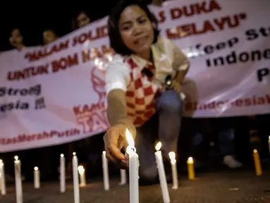 Massa dari Solidaritas Merah Putih menggelar aksi lilin dan tabur bunga di lokasi bom Terminal Kampung Melayu, Jakarta, Kamis (25/5). Aksi tersebut sebagai bentuk malam solidaritas duka untuk bom Kampung Melayu.(Liputan6.com/Faizal Fanani)