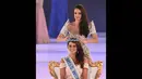 Miss World 2013, Megan Young saat memakaikan mahkota berwarna biru di atas kepala Rolene Strauss di London, Minggu (14/12/2014). (AFP PHOTO/Leon Neal)