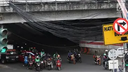 Kendaraan melintas di bawah Instalasi kabel menjuntai di Jalan Dewi Sartika, Jakarta Timur, Sabtu (19/1). Selain mengganggu keindahan kota, kondisi tersebut juga berbahaya karena dapat memicu hubungan pendek arus listrik. (Liputan6.com/Immanuel Antonius)