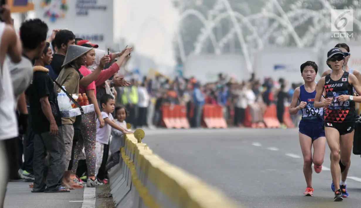 Warga menyaksikan lomba lari maraton putri Asian Games 2018 di kawasan MH Thamrin, Jakarta, Minggu (26/8). Meski Car Free Day ditiadakan, warga Ibu Kota tetap memadati kawasan MH Thamrin menyaksikan maraton Asian Games 2018. (Merdeka.com/Iqbal S. Nugroho)