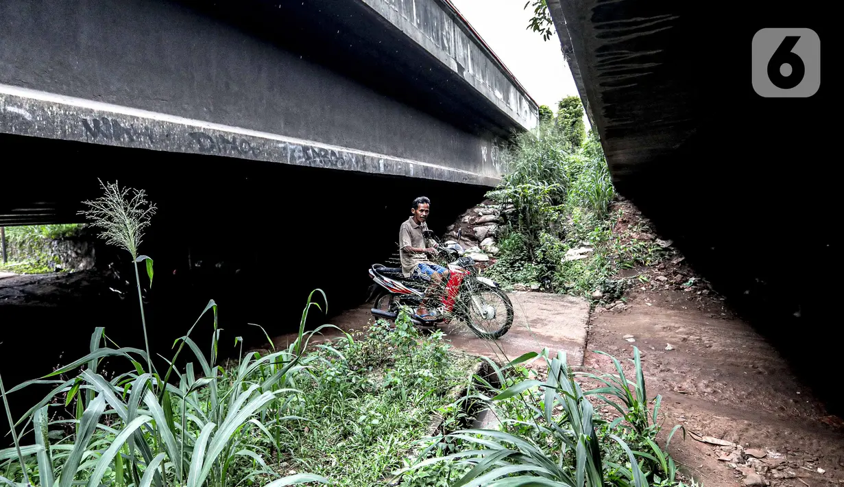 Pengendara sepeda motor melintas di kolong Tol Jagorawi, Cimanggis, Depok, Jawa Barat, Minggu (8/11/2020). Buruknya jalan dan minimnya penerangan membuat akses tersebut rawan aksi kejahatan. (Liputan6.com/Faizal Fanani)