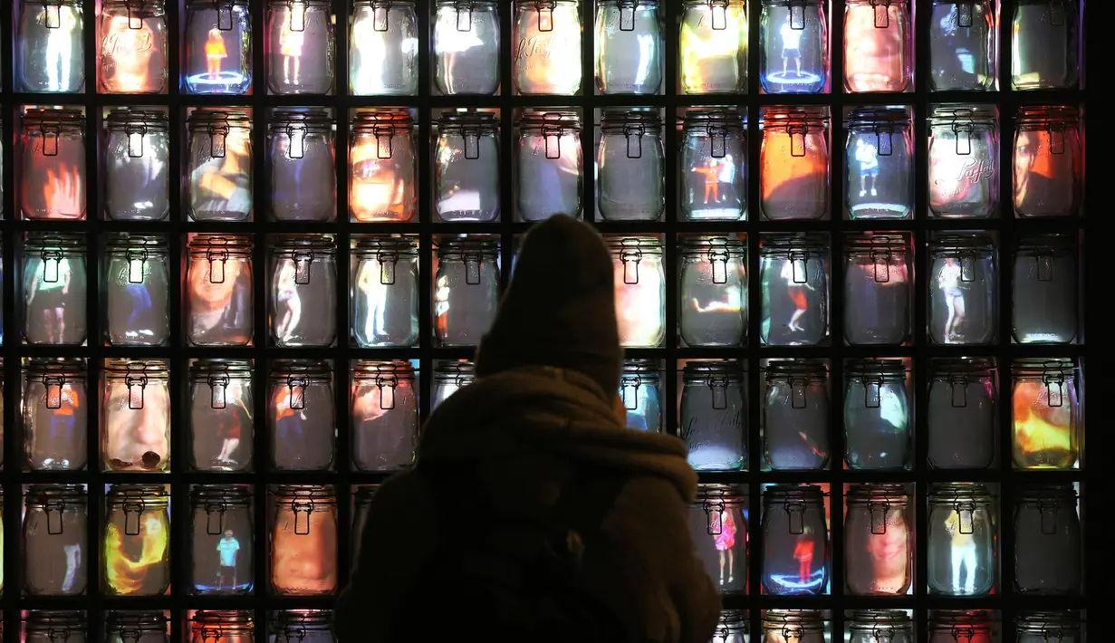 Seorang pengunjung melihat karya seni yang berjudul Supercube karya Stephane Masson yang dipamerkan dalam festival cahaya Lumiere London di area Pasar St James di London. (Jonathan Brady / PA via AP)