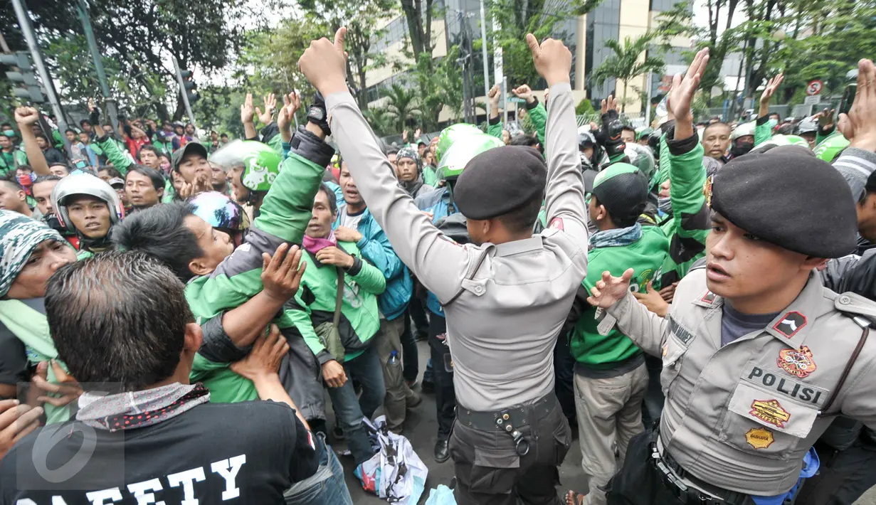 Petugas kepolisian mencoba menenangkan massa driver Gojek yang berunjuk rasa di kantor PT Gojek Indonesia, Kemang, Jakarta, Senin (3/10). Aksi dorong-dorongan driver Gojek dengan polisi sempat mewarnai unjuk rasa tersebut. (Liputan6.com/Yoppy Renato)
