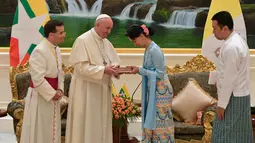 Pemimpin de facto Myanmar, Aung San Suu Kyi menerima cendera mata dari Paus Fransiskus di Naypyitaw, Selasa (28/11). Paus Fransiskus bertemu dengan Suu Kyi untuk membahas mengenai krisis kemanusiaan di Rakhine. (L'Osservatore Romano/Pool photo via AP)