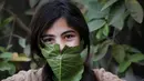 Seorang anak berpose dengan masker yang terbuat dari kubis saat dihibur oleh ibu mereka selama pandemi corona (Covid-19) di Beit Lahia di Jalur Gaza utara (16/4/2020). (AFP/Mohamed Abed)