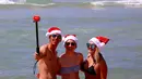 Para turis mengenakan topi natal berselfie saat merayakan hari Natal di Bondi Beach Sydney pada Hari Natal di Australia, (25/12). (REUTERS/David Gray)