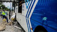 Petugas memeriksa kondisi bus Transjakarta yang menabrak separator busway di kawasan Bundaran Senayan, Jakarta, Jumat (3/12/2021). Kecelakaan mengakibatkan bagian depan bus Transjakarta rusak karena menghantam separator busway. (Liputan6.com/Faizal Fanani)