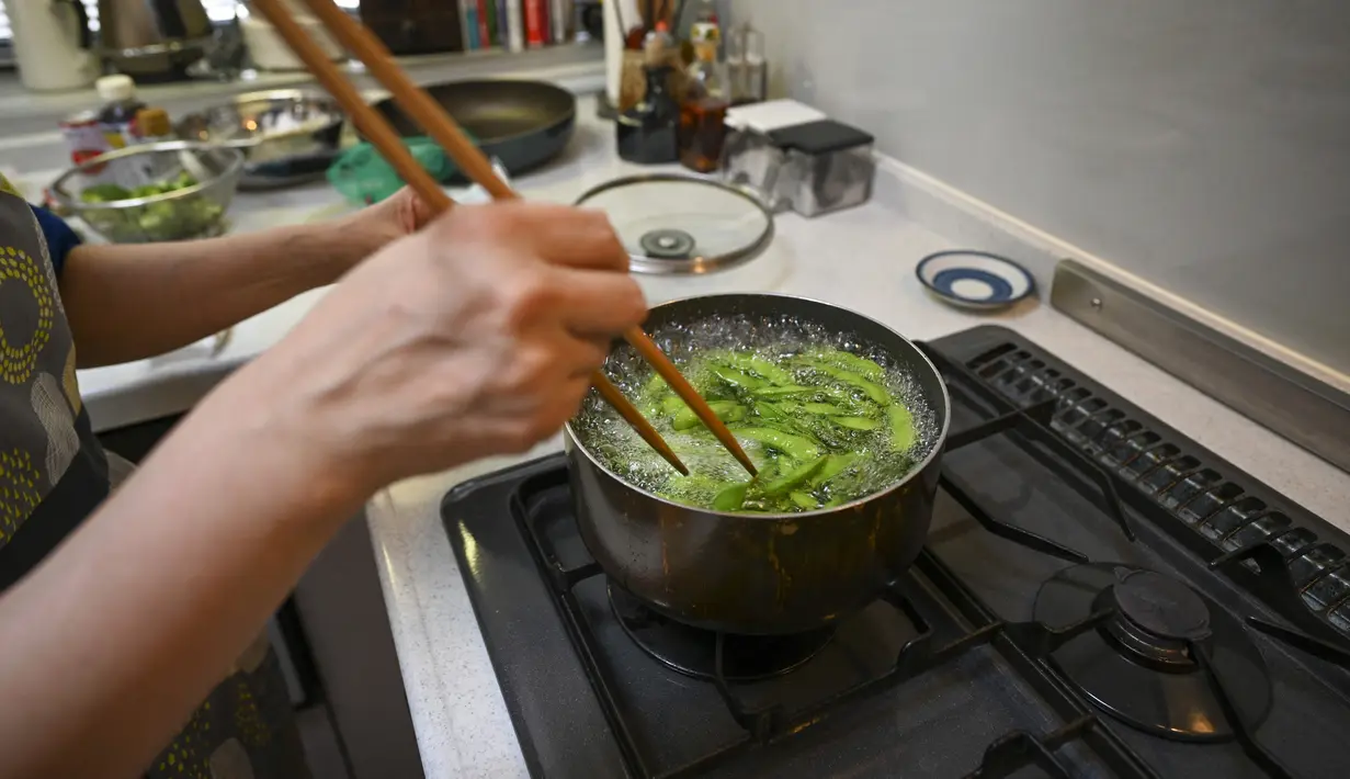 Pemenang kontes resep makanan Desa Olimpiade Tokyo 2020 Yoko Nishimura merebus kacang edamame di Tokyo, Jepang, 12 Juli 2021. Desa Olimpiade Tokyo 2020 jadi kesempatan atlet untuk mencicipi masakan Jepang yang terkenal. (KAZUHIRO NOGI/AFP)