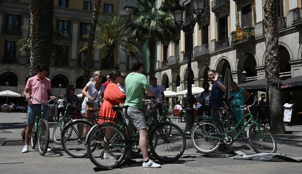 <p>Turis bersepeda mendengarkan pemandu wisata di Plaza Real di Barcelona, ​​pada 11 Mei 2022. Pengunjung sekali lagi memadati jalan-jalan sempit di kawasan Gothic Barcelona yang sempit saat perjalanan global bangkit kembali dari pandemi COVID-19, menghidupkan kembali kekhawatiran atas pariwisata massal di kota pelabuhan Spanyol. (LLUIS GEN / AFP)</p>