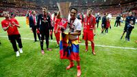 Carlos Bacca memperlihatkan trofi ke pendukung setia Sevilla di tengah perayaan gelar Liga Europa 2015 di Stadion Narodowy, Polandia, Kamis (28/5/2015). Sevilla memecahkan rekor meraih trofi Liga Europa terbanyak, yakni empat gelar. (Reuters/Carl Recine)