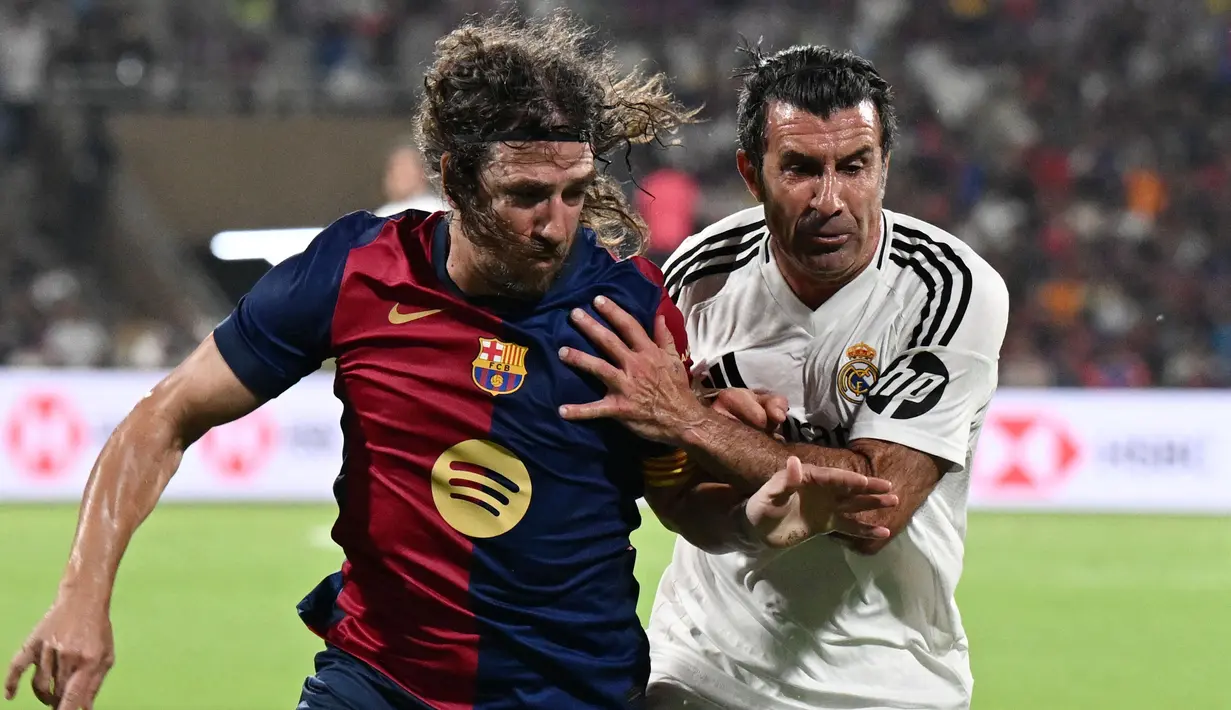 Legenda Barcelona, Carles Puyol (kiri) berebut bola dengan legenda Real Madrid, Luis Figo dalam laga persahabatan yang berlangsung di DY Patil Stadium, Navi Mumbai, India. (AFP/Punit Paranjpe)