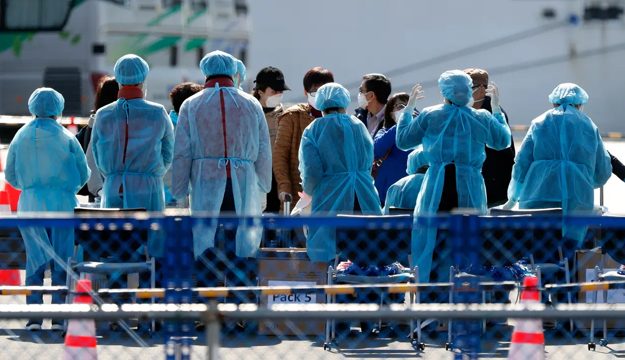 Petugas memeriksa penumpang yang turun dari kapal pesiar Diamond Princess yang dikarantina di Yokohama, Jepang, Jumat (21/2/2020). Dua orang Jepang dari kapal pesiar Diamond Princess dilaporkan meninggal dunia. (AP Photo/Eugene Hoshiko)