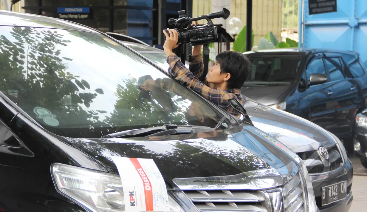 Seorang pewarta tampak merekam gambar mobil Toyota Alphard milik politikus Partai Demokrat, Sutan Bhatoegana, Jakarta, Selasa (17/3/2015). Penyitaan ini terkait penyidikan kasus dugaan korupsi di Kementerian ESDM. (Liputan6.com/Helmi Afandi)