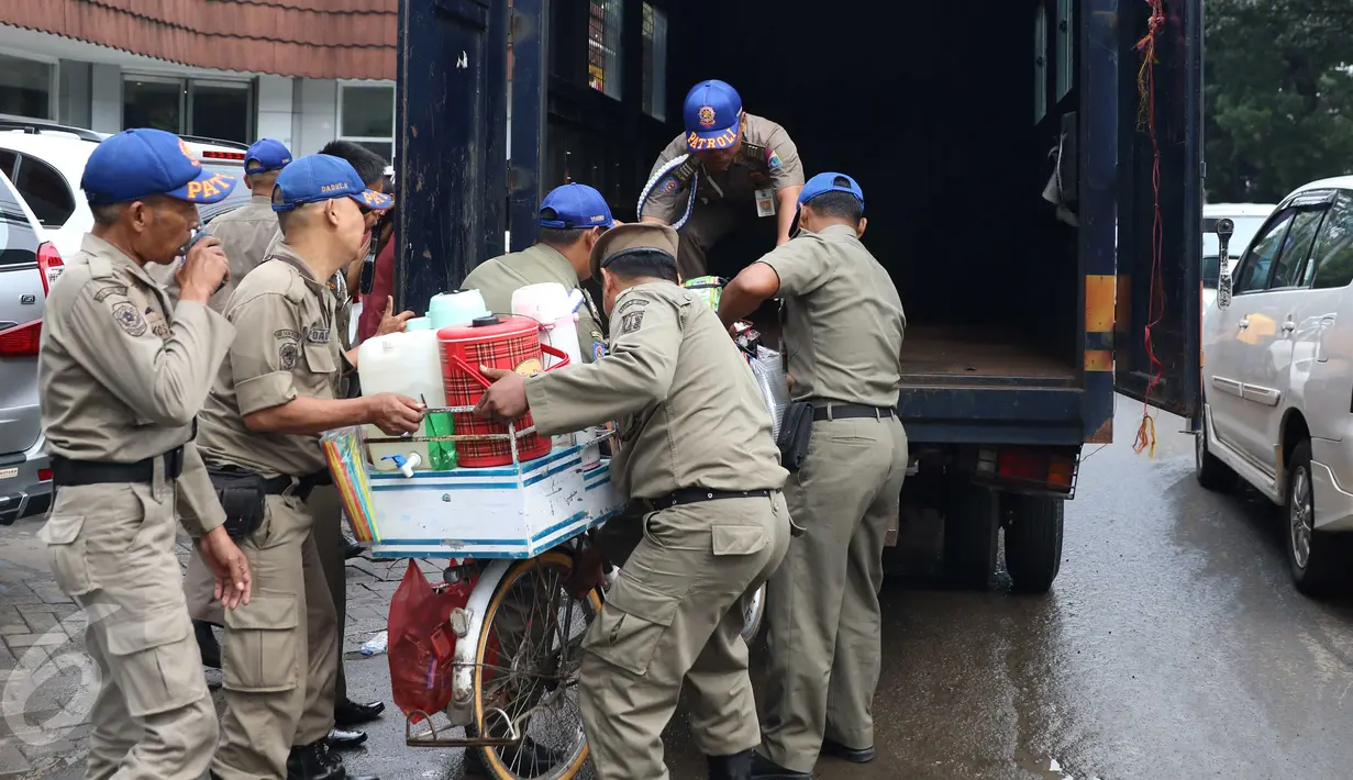 Petugas Satpol PP saat akan memasukkan barang dagangan milik pedagang kopi keliling ke dalam mobil dinas di kawasan SCBD, Jakarta, Senin (21/11). Satpol PP merazia dan menyita dagangan yang beroperasi di kawasan tersebut. (Liputan6.com/Gempur M Surya)