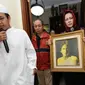 Pelayat membawa foto alm RMH Heroe Siswanto NS atau dikenal Sys NS di rumah duka, Jakarta, Selasa (23/1). Sys NS wafat diusia 61 tahun akibat serangan jantung. (Liputan6.com/Helmi Fithriansyah)