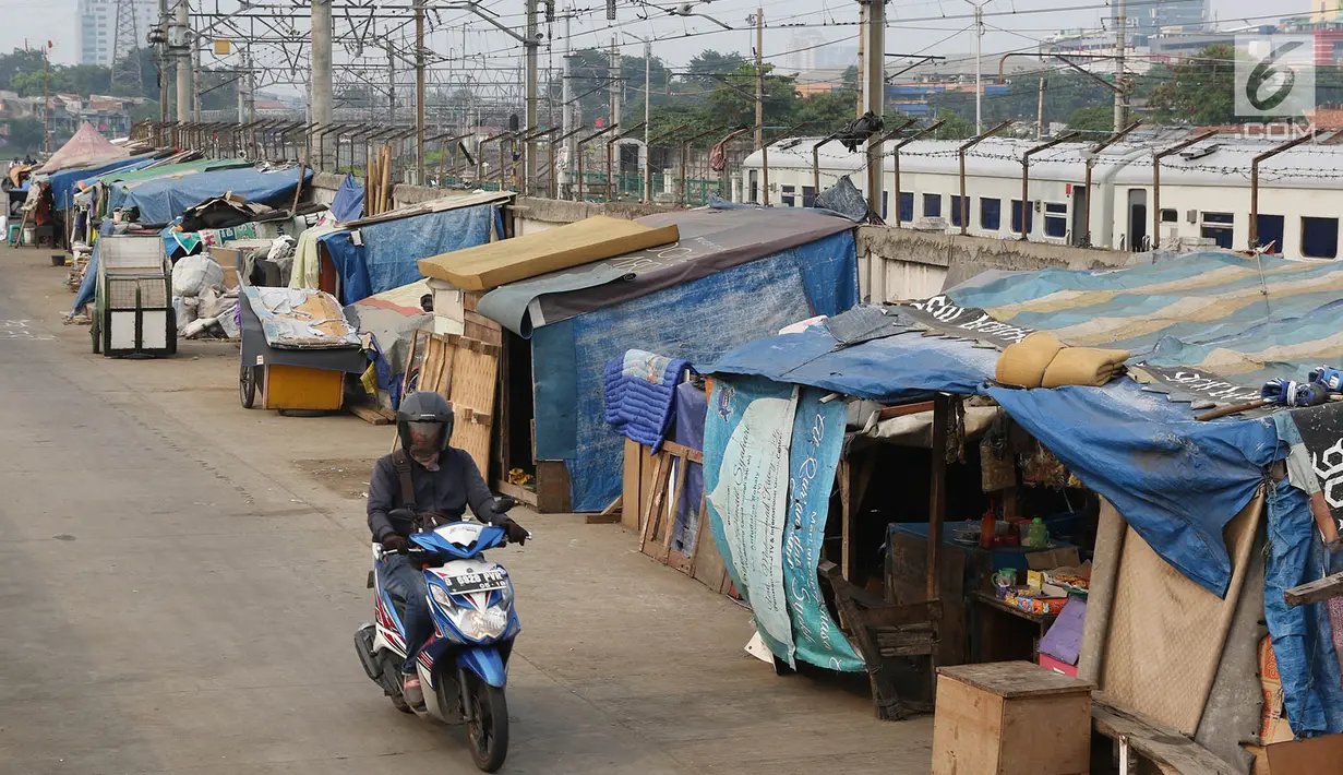 Pengedara melintas di depan gubuk liar yang berdiri di sepanjang jalur inspeksi Kanal Banjir Barat di Tanah Abang, Jakarta, Jumat (3/11). Kurangnya pengawasan menyebabkan daerah tersebut kembali dipenuhi gubuk liar. (Liputan6.com/Immanuel Antonius)
